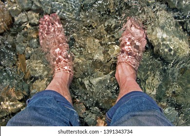 Feet immersed in the clear water of a mountain stream 