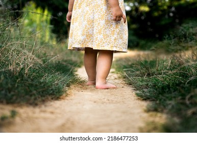 Feet Of A Little Girl On A Sandy Path