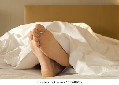 Feet Of A Man Lying Down On Bed