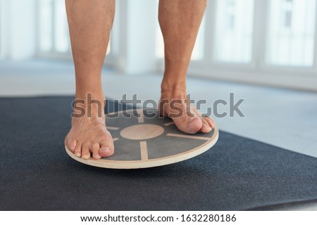 Feet of a man working out on a balance board in a gym to strengthen and tone his muscles in a low angle view