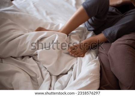 feet of a mother and her son hugging on a bed with a white blanket