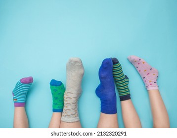 Feet of mothers and children with socks in different colors on a light blue background. Family concept. Support and awareness of people with Down syndrome. March 21. Copy space.
