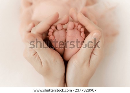 Feet of a newborn baby in the mother's arms. legs of a newborn baby in his hands. baby's legs. baby feet on background