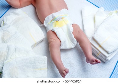 Feet Of Newborn Baby On Changing Table With Diapers. Cute Little Girl Or Boy Two Weeks Old. Dry And Healthy Body And Skin Concept. Baby Nursery