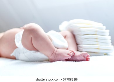 Feet Of Newborn Baby On Changing Table With Diapers. Cute Little Girl Or Boy Two Weeks Old. Dry And Healthy Body And Skin Concept. Baby Nursery