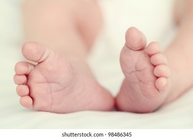 Feet of a newborn baby sleeping on white blanket. Soft focus, very shallow DOF.