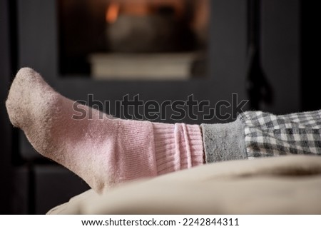 feet on cushion with dirty pink socks from walking barefoot and pajamas, behind fighting stove with burning flame