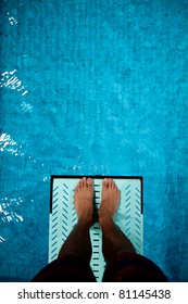 feet on diving board over pool
