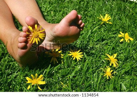 Feet on grassy field with yellow daisies