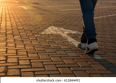 Feet on the white road arrow in the rays of the setting sun close up. Forward movement - Shutterstock ID 611844491