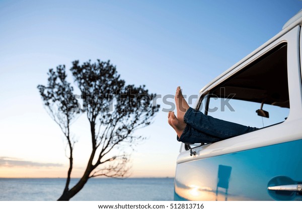 Feet out of camper van
window at dusk