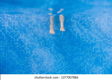 Feet of people moving under the water in the pool. Children legs. Summer. Funny underwater legs in swimming pool, under water view of women or kids, vacation and sport concept.