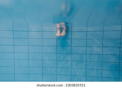 Feet of people moving under the water in the pool. Children legs. Summer. Funny underwater legs in swimming pool, under water view of child or kids, vacation and sport concept. Down view.