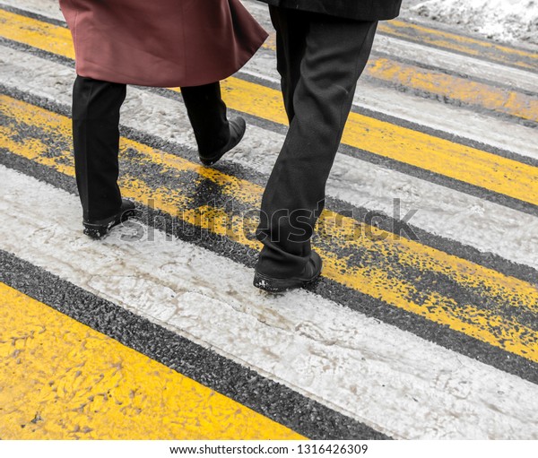 Feet of\
people at a pedestrian crossing in winter\
.