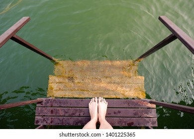 Feet and Purple Pedicure of Woman in Green Water, Top view. Beautiful Asian Young Female Body Legs and Barefoot on a Wooden Bridge Background. Cropped Image of People Foot Under Aqua Water on Summer.