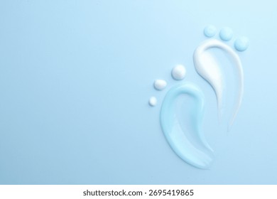 Feet shape made of samples of different cosmetic products on light blue background, flat lay. Space for text