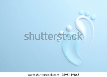 Feet shape made of samples of different cosmetic products on light blue background, flat lay. Space for text