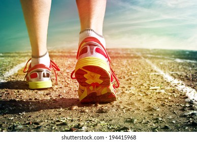 Feet In Sneakers Men Running On The Asphalt Against The Sky. Toning Effect