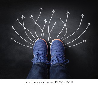 Feet with sneakers standing next to chalk arrows on blackboard taking decisions for the future - Powered by Shutterstock