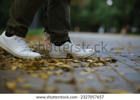 Feet sneakers walking on fall leaves Outdoor with Autumn season nature on background Lifestyle Fashion style