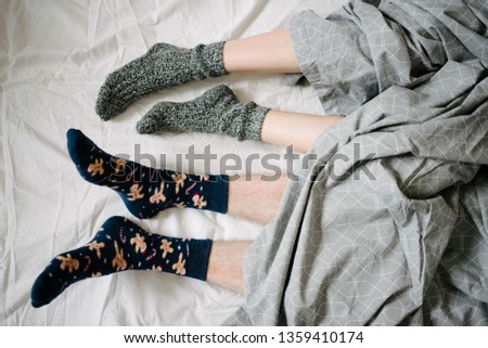 Feet in socks under a blanket in bed