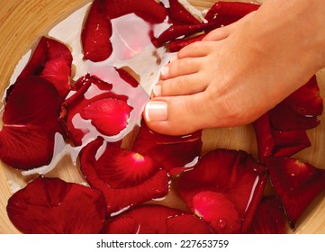 Feet Spa. Pedicure Concept. Beautiful healthy woman's feet massage. Female legs in water with rose petals - Powered by Shutterstock