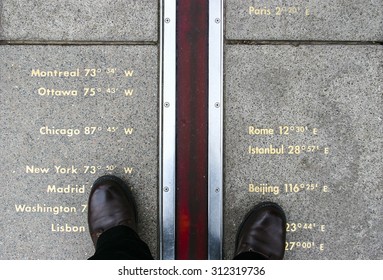 Feet stand on opposite sides of the Prime Meridian. Greenwich, London, UK.