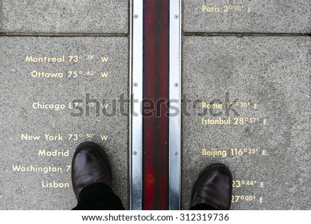 Feet stand on opposite sides of the Prime Meridian. Greenwich, London, UK.