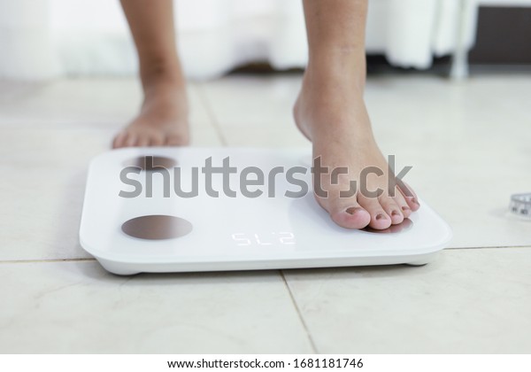feet standing\
on electronic scales for weight control. Measurement instrument in\
kilogram for a diet\
control