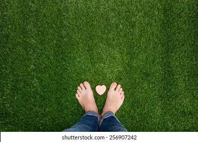 Feet standing on grass with small heart
