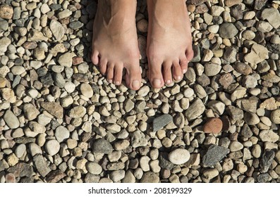 Feet standing on pebble beach surface