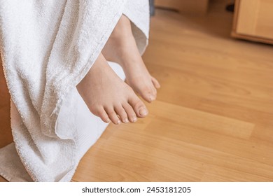 Feet sticking out of soft white towel on the bed at home, close up, cropped - Powered by Shutterstock