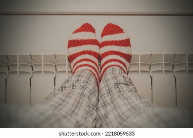 Feet In Striped Socks On The Heating Radiator At Home