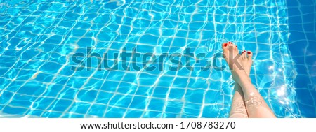Feet in swimming pool water. Selfie of legs and barefoot with red pedicure and manicure nails on blue sea background. Vacation at summer holiday.