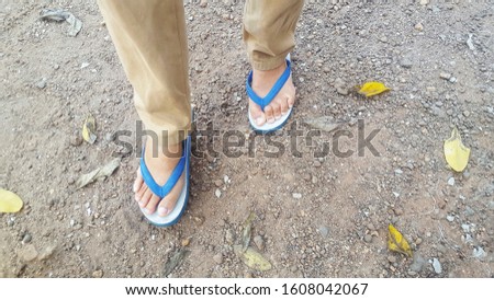 The feet that wear blue slippers on the ground.