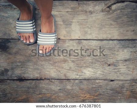 Feet that wear fashion slippers, standing on the old plank floor, free space for fashion messages, sandals
