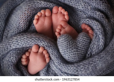 Feet Of Three Newborn Babies In A Soft Blanket. Heart In The Legs Of Newborn Triplets. Studio Photography.