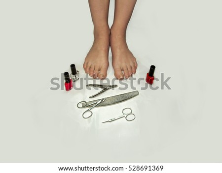 Feet and toes in poor condition and they need in a pedicure. Scissors, nail file, Cuticle Nippers, nail polish stand around the female  feet