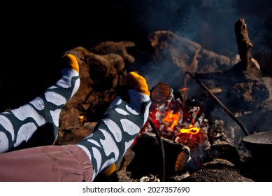 Feet warm by the fire. Feet in socks on a background of fire. The concept of warmth, comfort and relaxation.