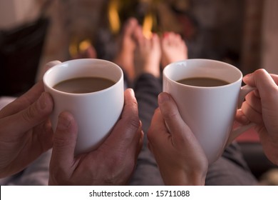 Feet warming at fireplace with hands holding coffee