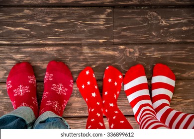 Feet Wearing Christmas Socks On Wood Floor. Happy Family At Home. Xmas Holidays Concept