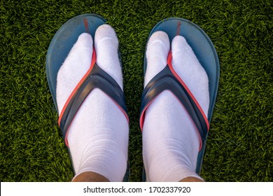Feet in white socks and flip flops. Jandals.