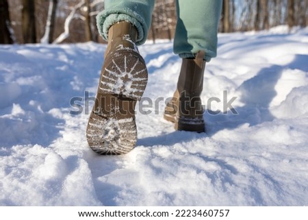 Feet in winter boots walking on crisp, fresh snow. Walking on snow with winter boots. Warm clothes. Close-up.