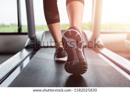 Feet of woman exercise workout running on treadmill at fitness gym