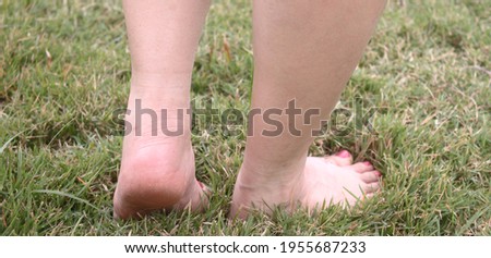 A   feet of woman walking on the grass to exercise in the morning,closeup shot,selective focus at left heel. Health and Relaxation Concepts
