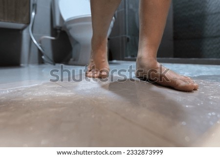 Feet of woman walking on wet floor in bathroom,wet bathroom floor after showering,risk of slipping and falling on slippery surface,careful stride,walk carefully,concept of accident and injury in home