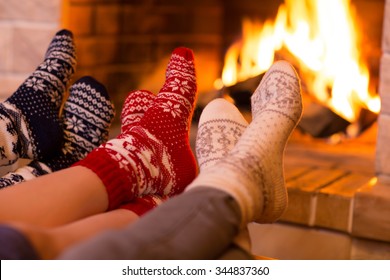 Feet in wool socks near fireplace in winter time