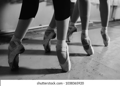 feet of young ballerinas in pointe shoes close-up against the backdrop of a ballet class