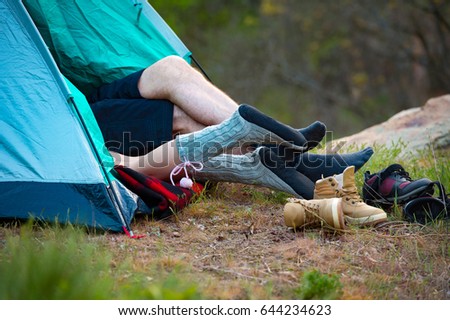 Feet of a young couple lying in a tent. Camping, travel, tourism, hike and people concept.