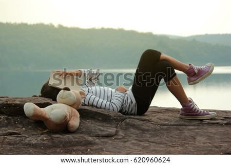Feet of young girl sleep in the park on nature, Relax time on holiday in beautiful nature concept travel ,Relaxing woman at nature in sunset. Asian girl and teddy bear.